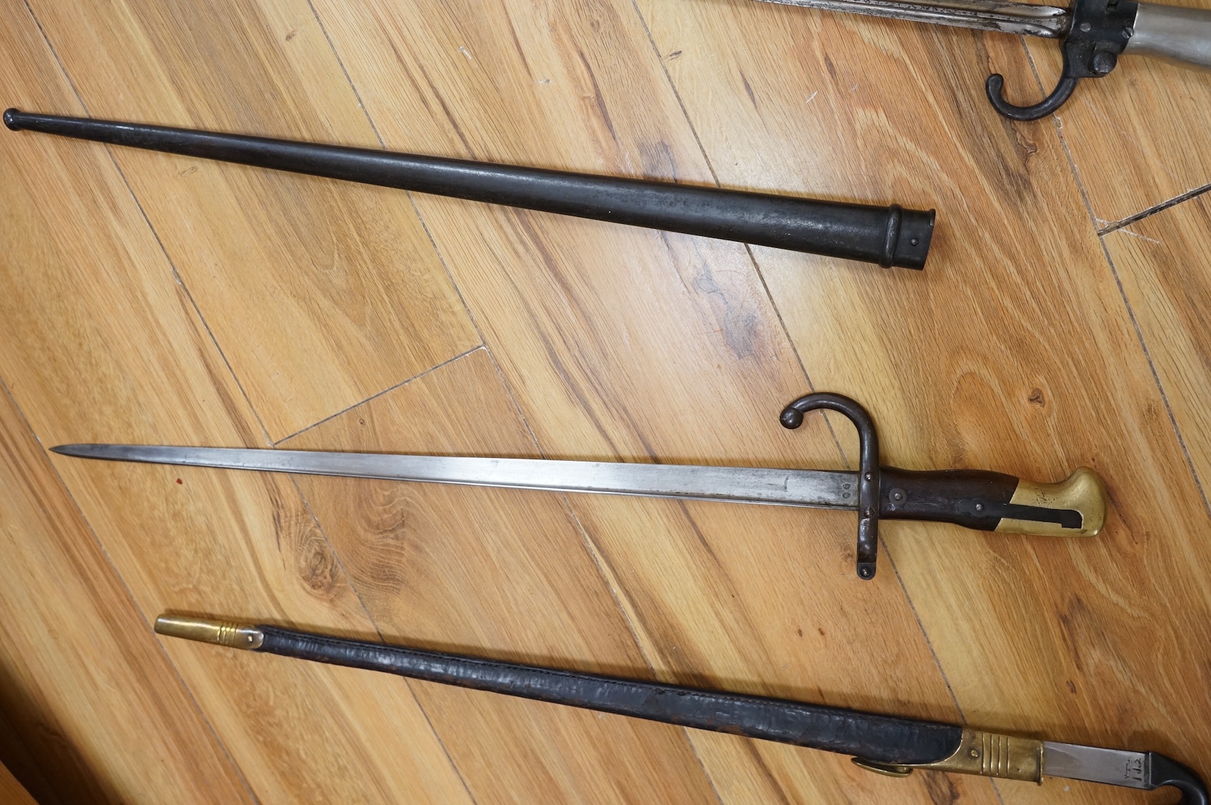 Three bayonets; a gras bayonet, a Lebel bayonet and an Indian Enfield style triangular socket bayonet, all in the original scabbards